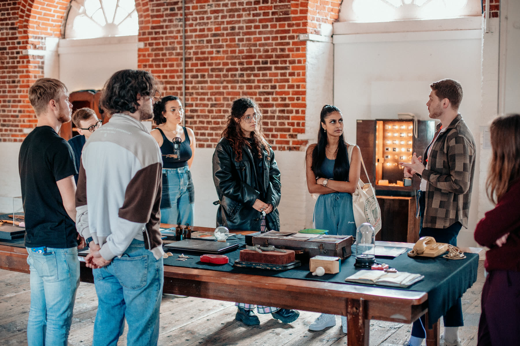A group gathered around a table of archival objects during a Play Office artist development session inside Boathouse 5.